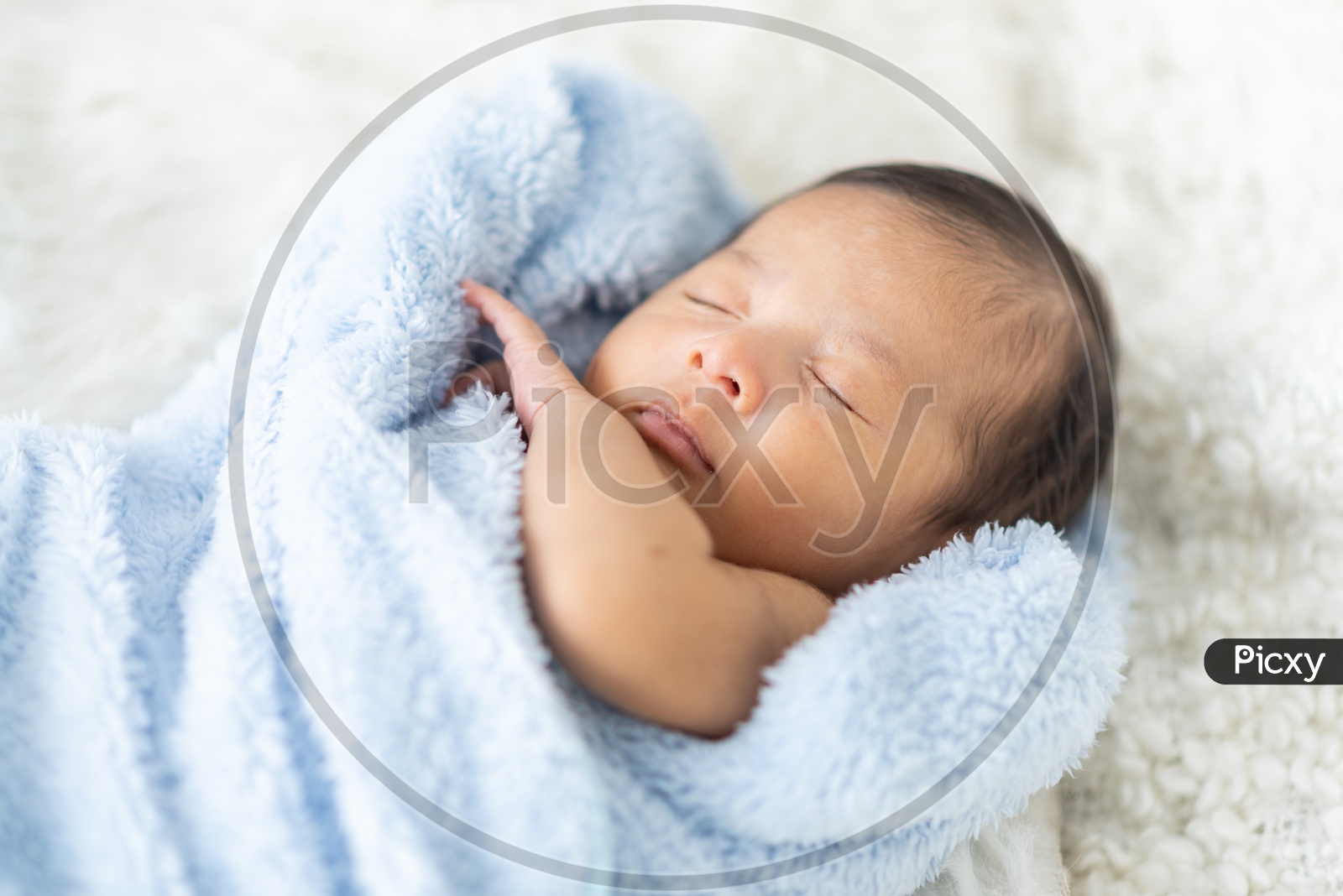 Newborn baby curled up in a towel sleeping