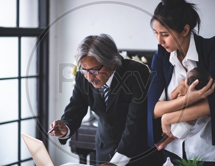 Young Asian Businesswoman Mother working at the office and taking care of her Baby