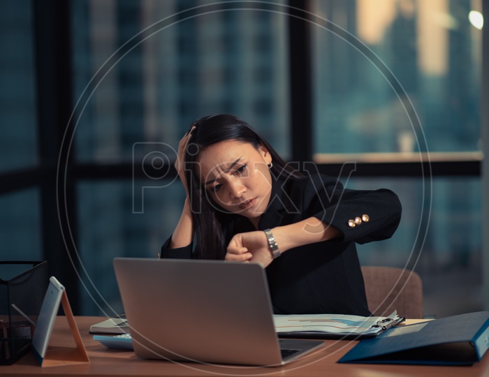 Young Asian Businesswoman working overtime in office, Employee checking Time