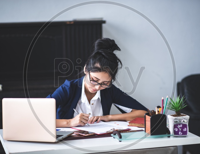 Young Asian Businesswoman filling Documents at workplace