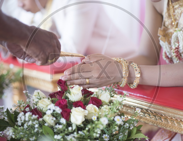 Close up of woman's hands with gold bangle during Thai wedding