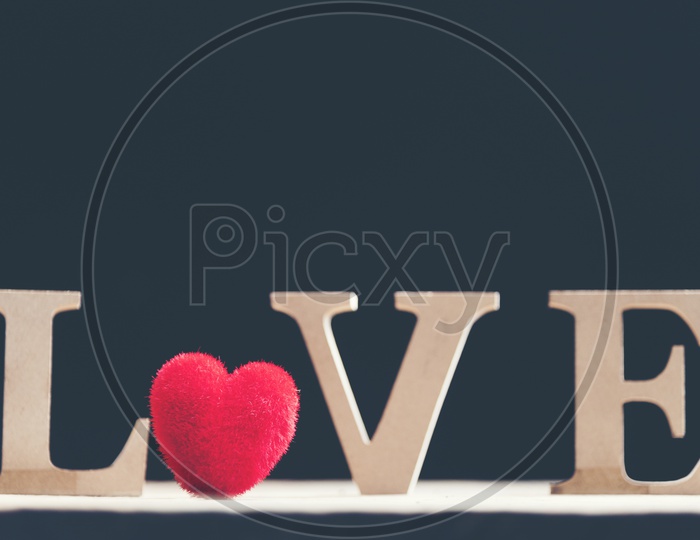 Close up of soft fur heart shaped toy and wooden letters forming word LOVE