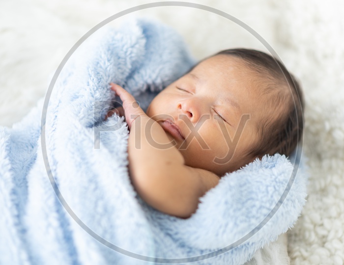 Newborn baby curled up in a towel sleeping