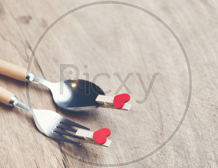 Love and  Valentines  Day Concept With Red Heart Shape Tagged To Spoon and Fork On an Wooden Table Background With Vintage Filter