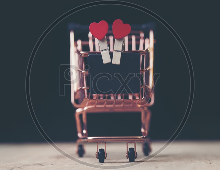 Heart shaped wooden clips in a trolley toy with black background - Valentines Day background