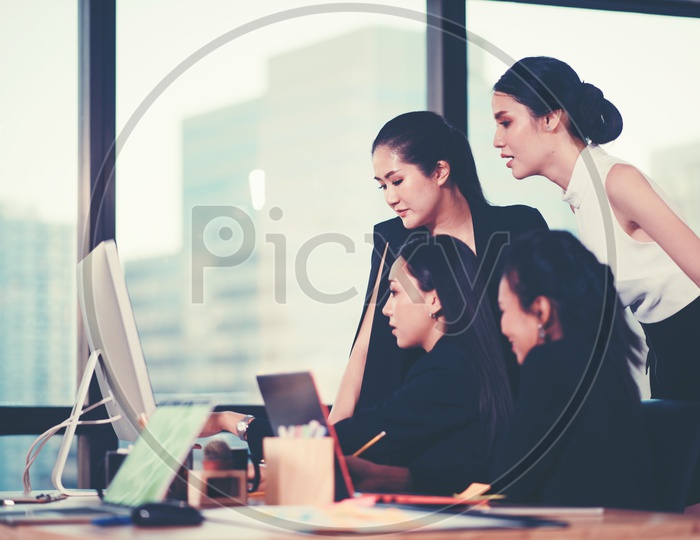 Young Asian Women Discussing Business Ideas on Laptop