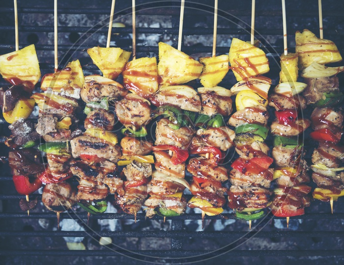 Grilled beef and vegetable BBQ skewers on the black background, top view, vintage filter image