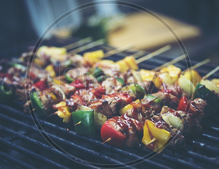 Grilled beef and vegetable BBQ skewers on the black background, side view, vintage filter image