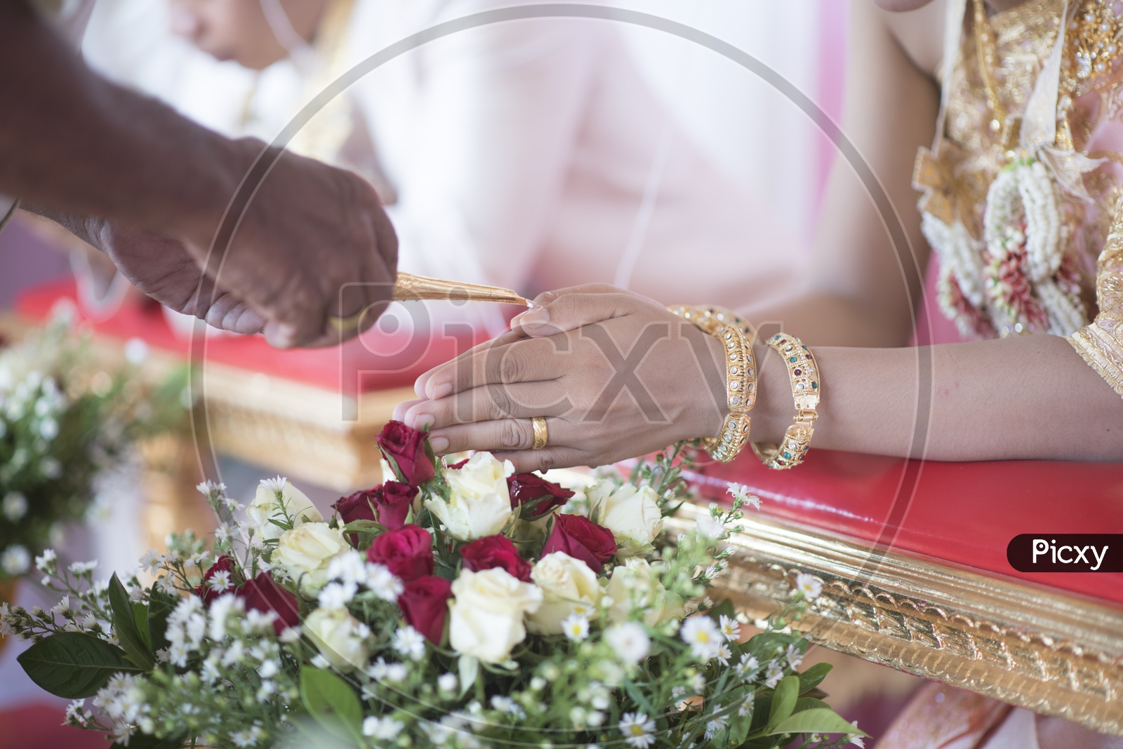 Close up of woman's hands with gold bangle during Thai wedding