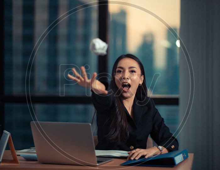 Angry and Frustrated Young Asian Businesswoman throwing Paper