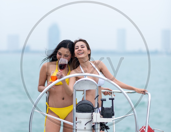 Young Asian Women in Bikini on a Yacht drinking Wine