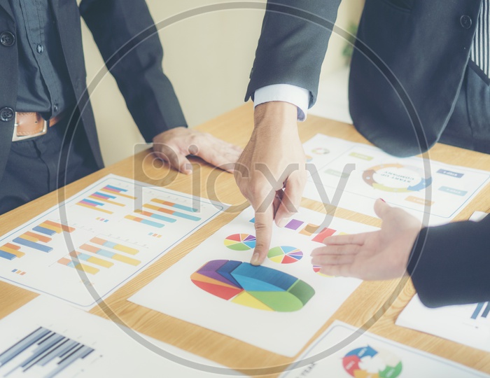 Business Entrepreneurs Discussing Business Plans With Growth Data With Charts And Figures on a Office Desk Closeup