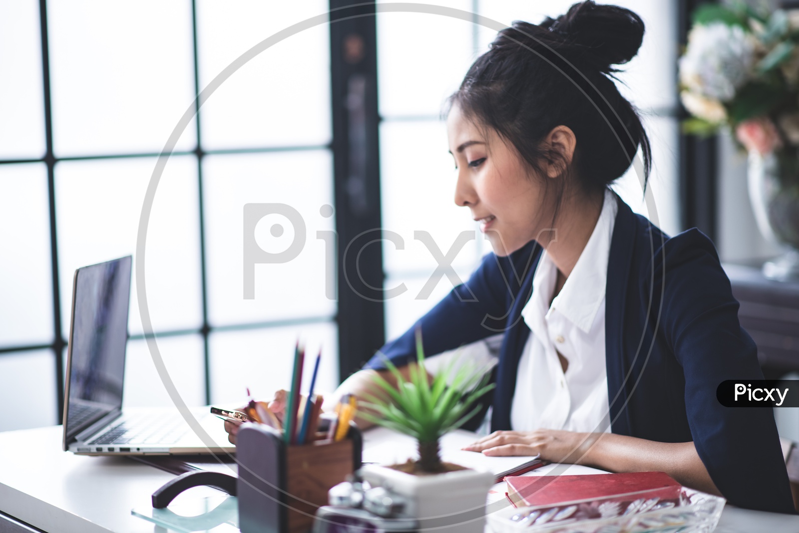 Portrait of Pretty Young Asian Businesswoman using Mobile or Smartphone at Workplace