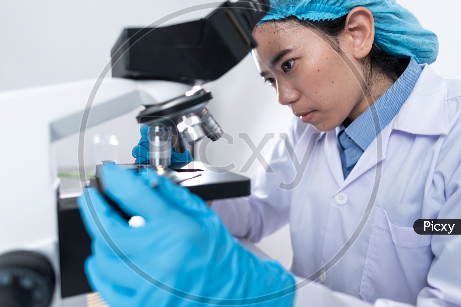 Asian Female Scientist or Medical Student Analyzing Sample through Microscope