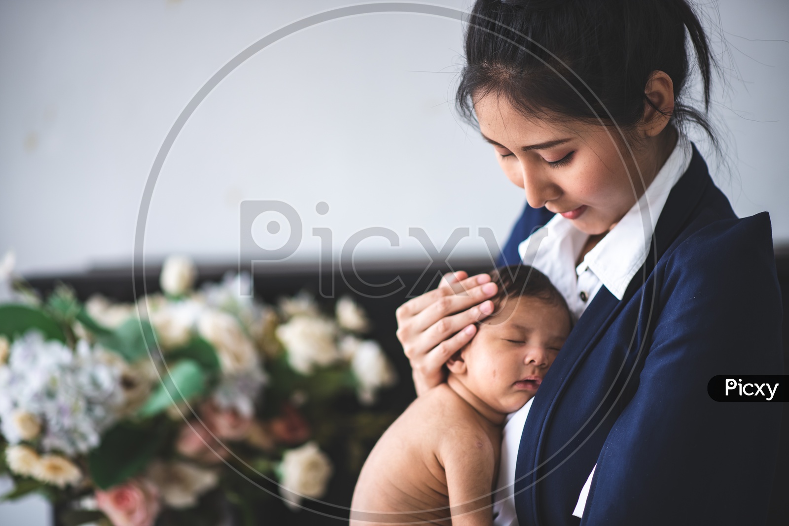 Portrait of Young Asian Businesswoman Taking Care of her Baby at Workplace