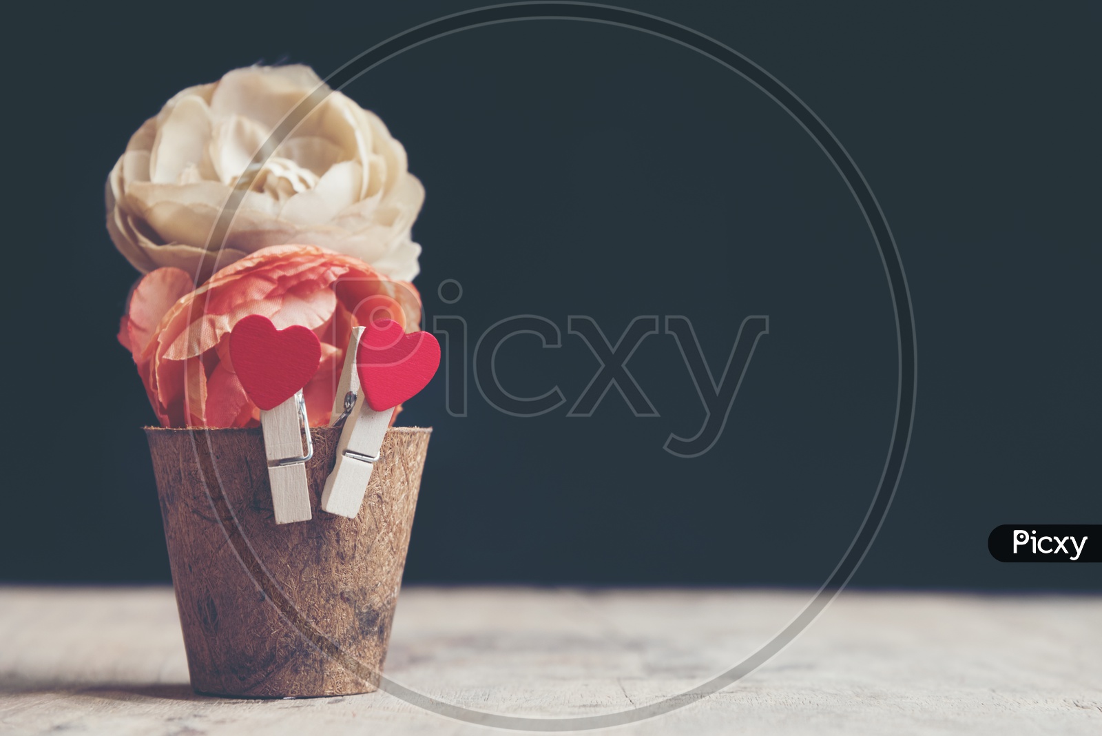 Rose flowers in a wooden cup with heart shaped clip