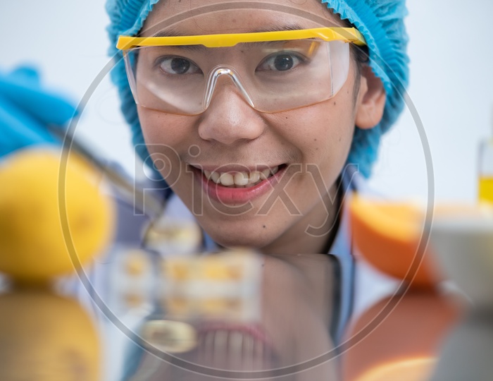 Young Asian Woman Scientist Holding Fish Oil Pill Or Capsule with Oranges in Foreground