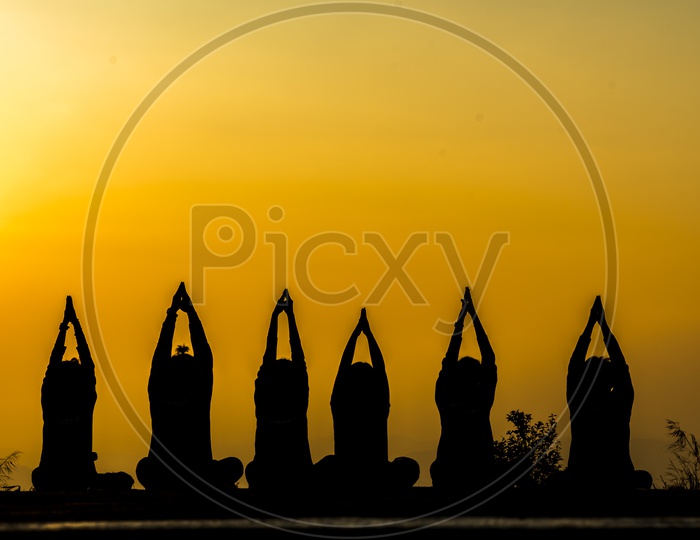silhouette of  group of People practicing yoga on the beach at sunset