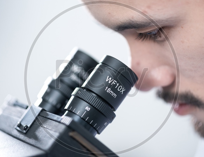 Closeup Shot of a Man Looking through Microscope