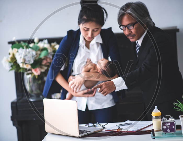 Young Asian Businesswoman Working at Office while holding her baby in arms