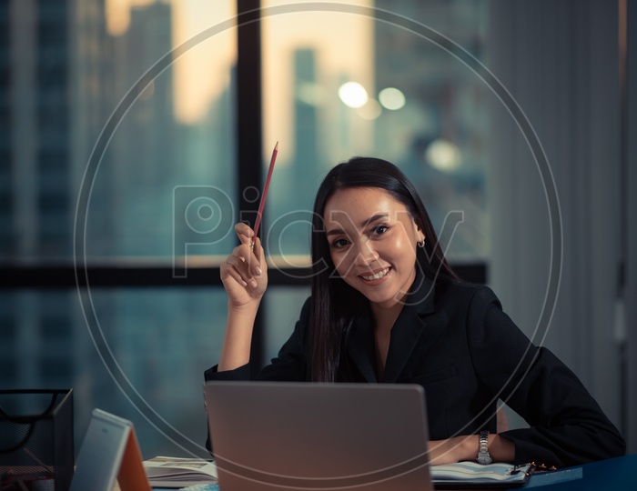 Happy Young Asian Businesswoman working on Laptop at Workplace
