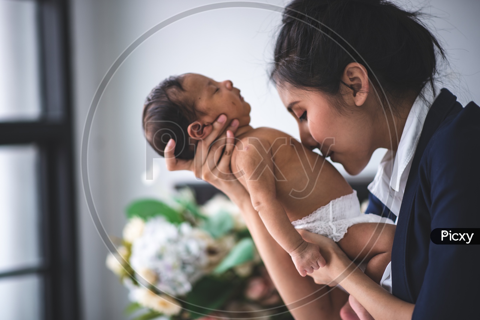 Young Asian Mother holding her newborn baby and kissing