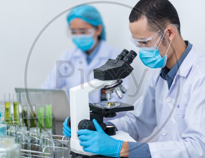 Asian Male Scientist Testing Algae fuel or BioFuel on Microscope at Chemical Laboratory