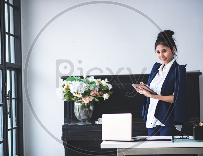 Portrait of Pretty Young Asian Businesswoman working on Tablet at Workplace