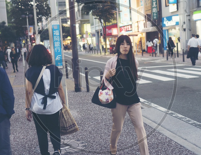 A Japanese Woman walking carrying a handbag in the street in Fukuoka, Japan