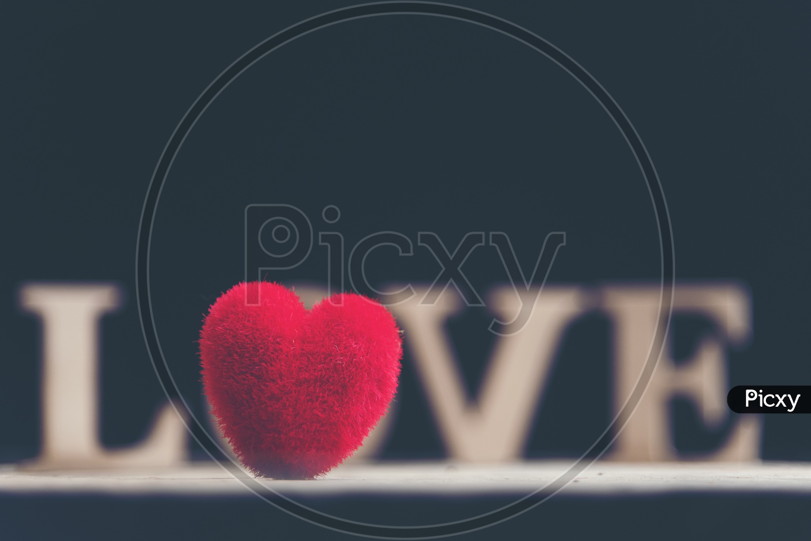 Close up of soft fur heart shaped toy and wooden letters forming word LOVE