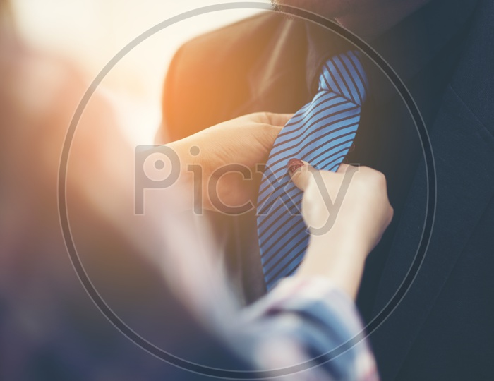 Close-up of a woman tying neckties to a man