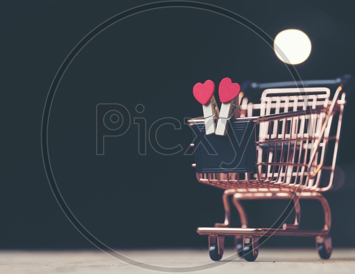 Heart shaped wooden clips holding a mini slate in a trolley toy with black background - Valentines Day background