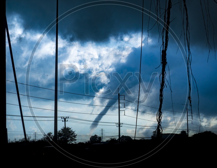 Silhouette Of Electric Wires And Poles With Dark Clouds In Sky As a Background