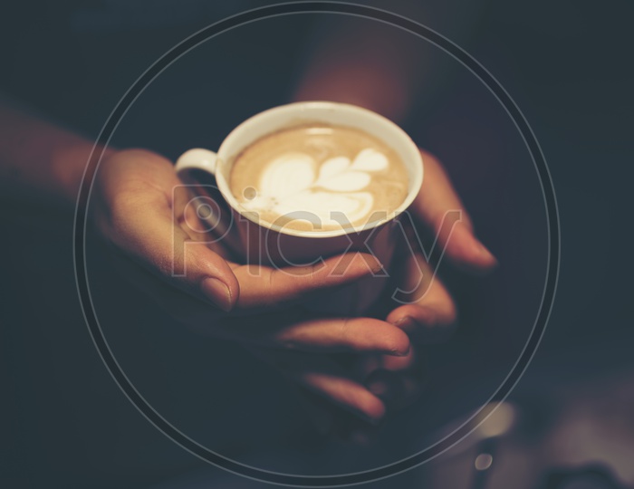 Hand Holding a Coffee Cup With Coffee Latte Art