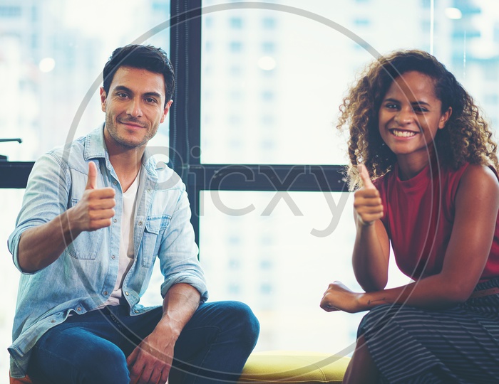 Smiling Young Asian Man and Woman Showing Thumbs up at Workplace