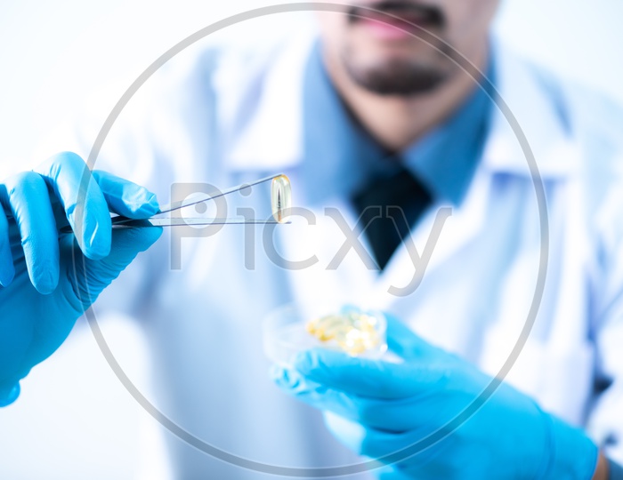 Young Asian Male Scientist Holding Fish Oil Pill Or Capsule In Hand, Healthy Nutrition