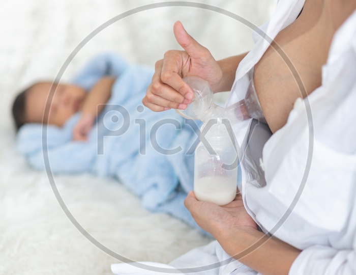 Asian Mother pumping breastmilk into the baby bottle