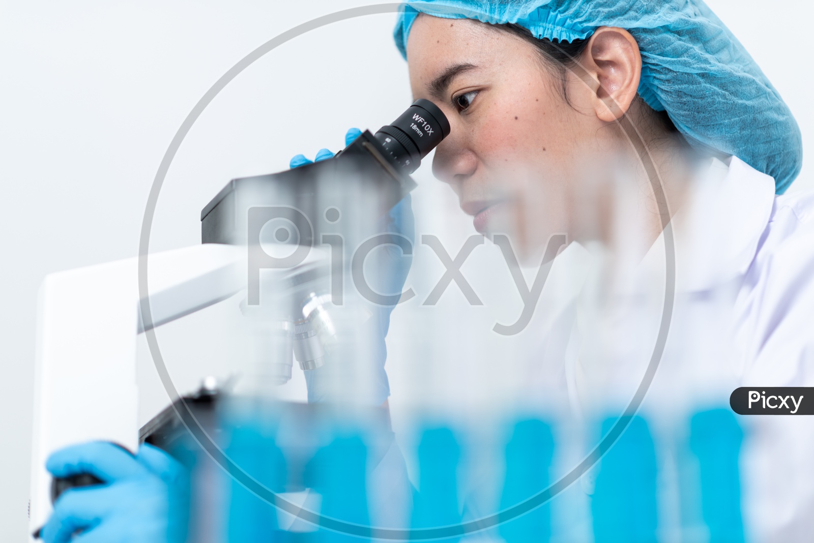 Young Asian Female Medical Student or Scientist Analyzing Sample through Microscope