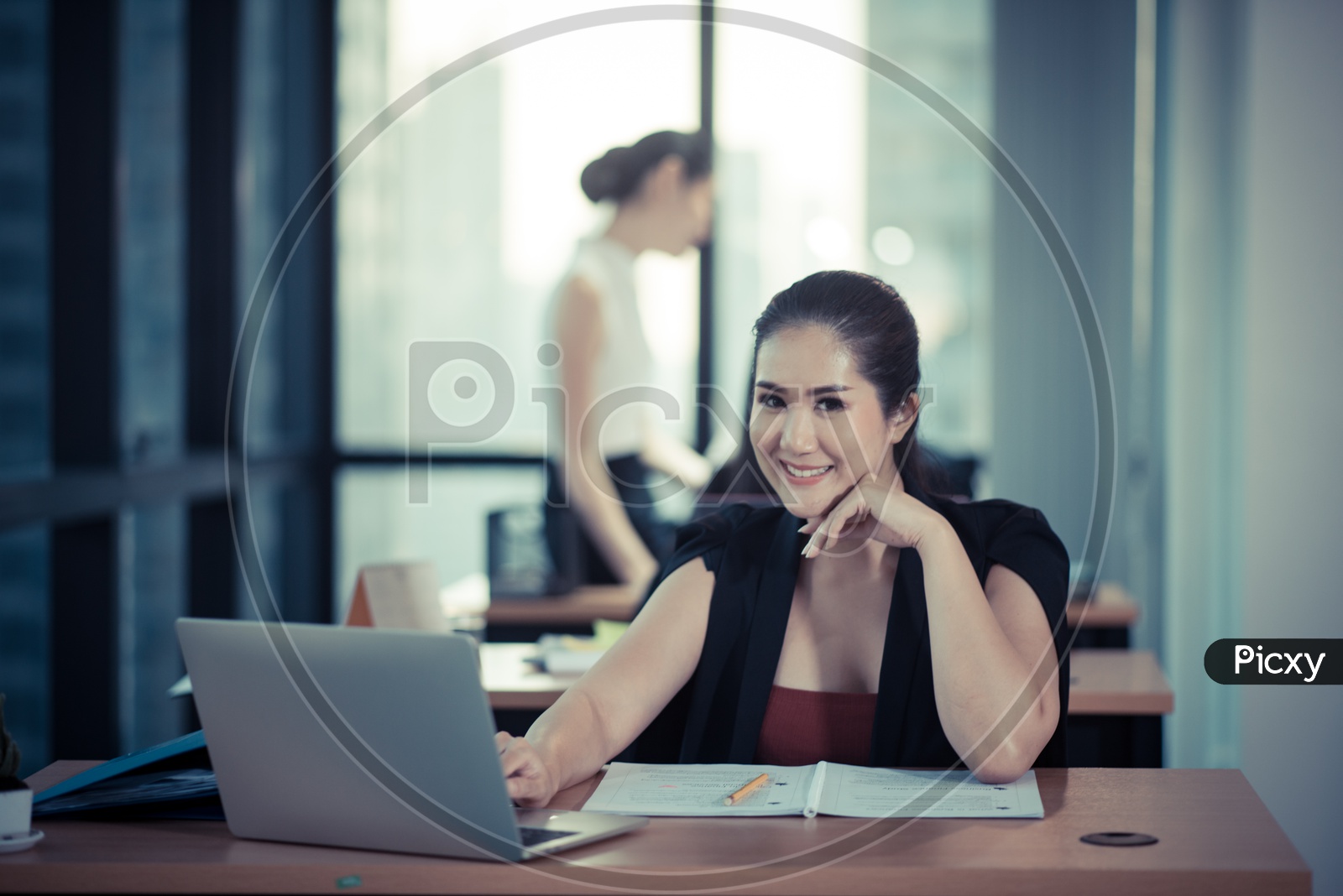 Smiling Young Asian Businesswoman working on Laptops at Workplace