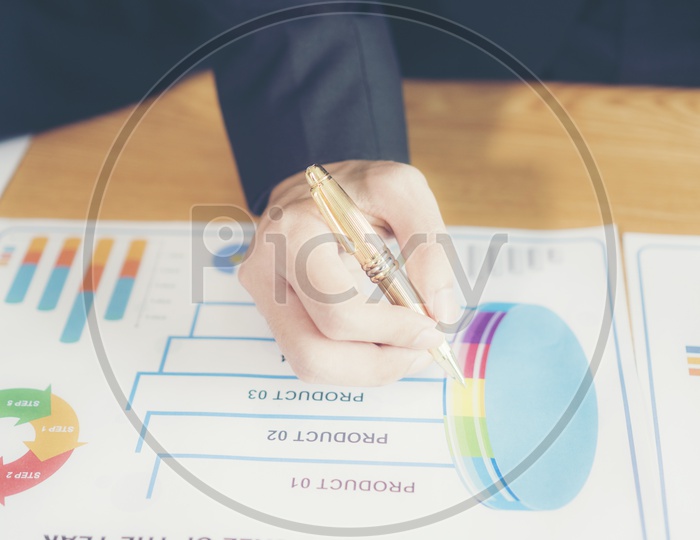 A male hand with a pen on a business document during discussion at meeting
