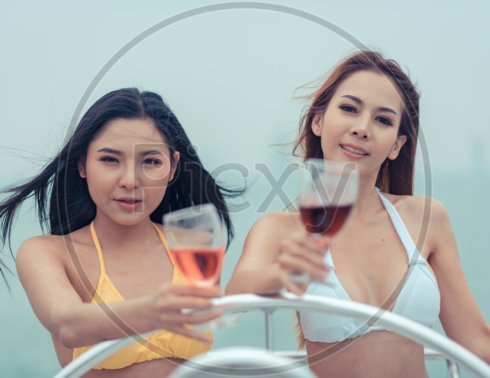 Beautiful Young Asian women in bikini sipping wine on a yacht