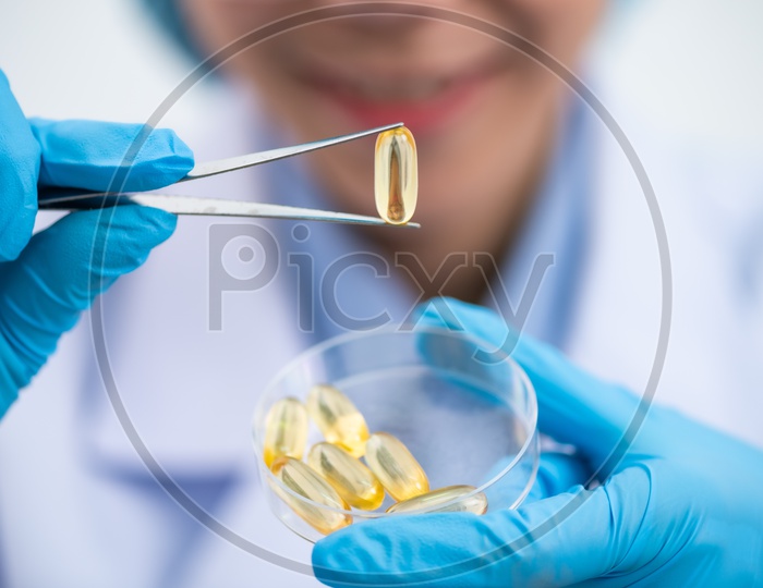 Young Asian Woman Scientist Holding Fish Oil Pill Or Capsule In Hand, Healthy Nutrition