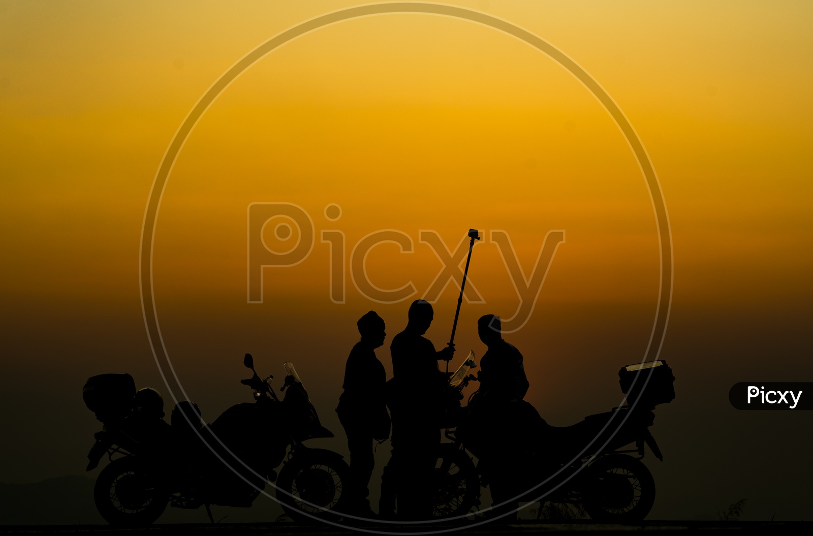 Silhouette Of Group Of Young Adventure Travelers Over sunset Background