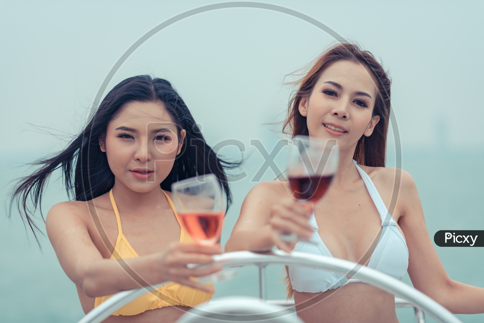 Beautiful Young Asian women in bikini sipping wine on a yacht