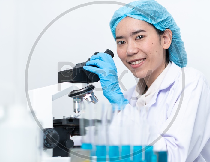 Young Asian Female Medical Student or Scientist Analyzing Sample through Microscope