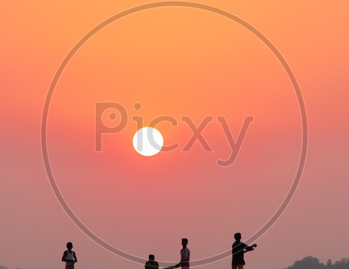 Silhouette of Child Playing Cricket in a Dried River Channel or valley With Bright Red Sun