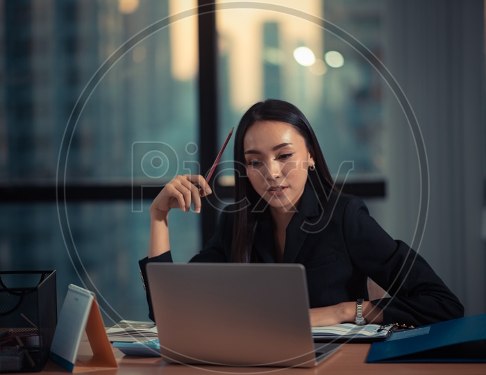 Confident Young Asian Businesswoman working on Laptop at Workplace