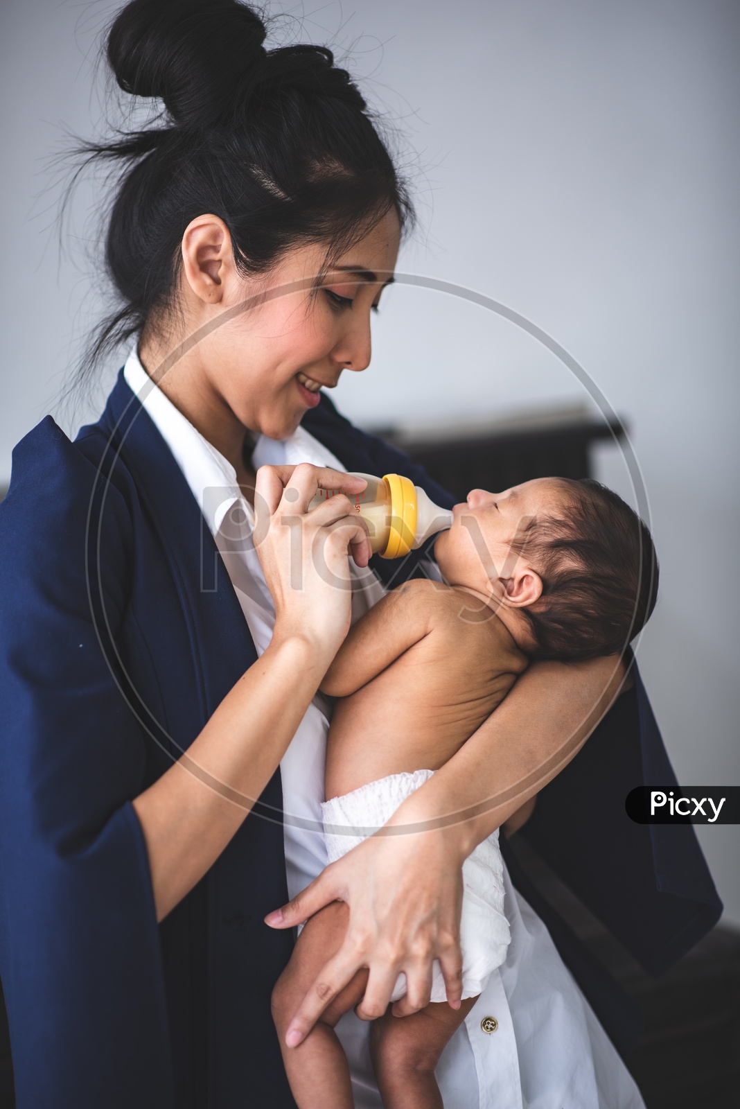 Young Asian Mother Feeding her Baby while at the Workplace