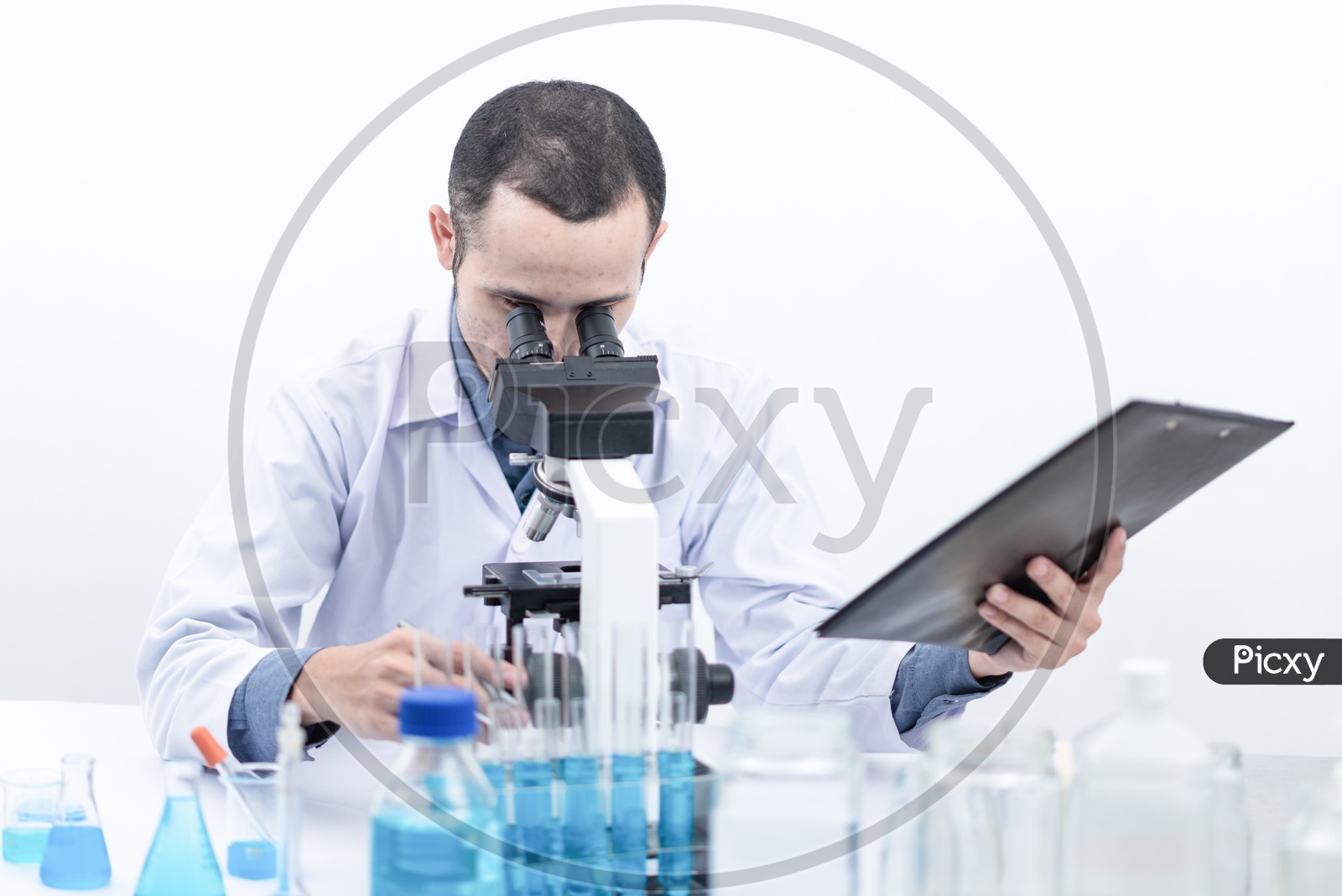 Young Asian Scientist or Medical Student Analyzing Sample through Microscope at Laboratory