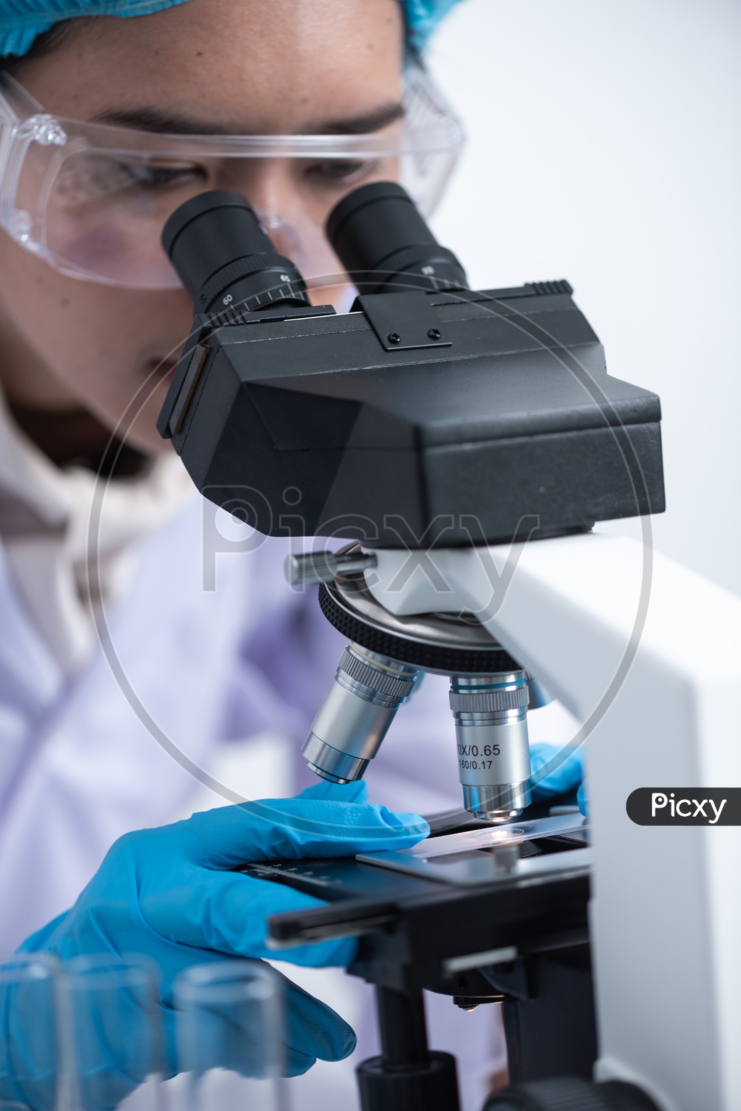 Young Asian Scientist or Medical Student Analyzing Sample through Microscope at Laboratory